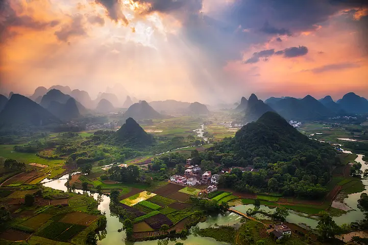 Light beams piercing the sky as seen from the top of Cuipingshan Hill in Yangshuo, China.