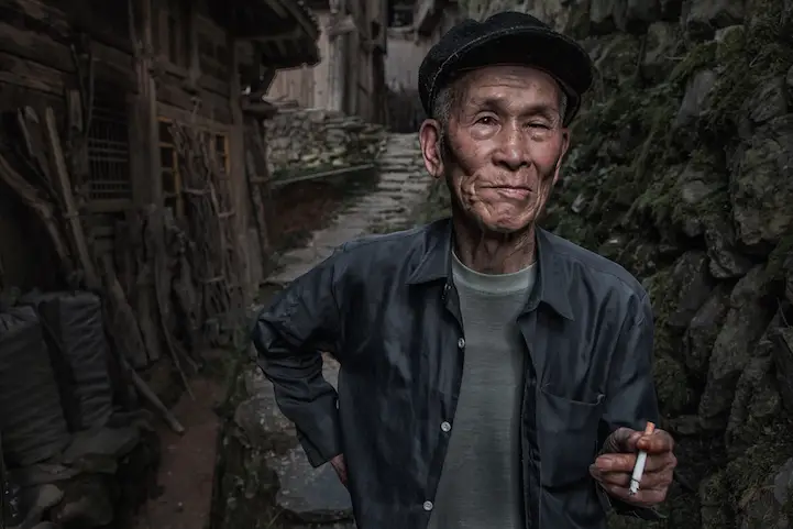 Chinese man from the Longji area takes a break outside his house.