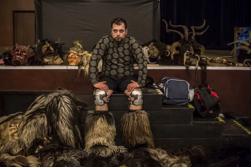 KAPLICE, CZECH REPUBLIC - DECEMBER 12: A participant dressed as the Krampus creature rests in the backstage before Krampus gathering on December 12, 2015 in Kaplice, Czech Republic. Krampus, also called Tuifl or Perchten, is a demon-like creature represented by a fearsome, hand-carved wooden mask with animal horns, a suit made from sheep or goat skin and large cow bells attached to the waist that the wearer rings by running or shaking his hips up and down. Krampus has been a part of Central European, alpine folklore going back at least a millennium, and since the 17th-century Krampus traditionally accompanies St. Nicholas and angels on the evening of December 5 to visit households to reward children that have been good while reprimanding those who have not. However, in the last few decades the western Austrian region of Tyrol in particular has seen the founding of numerous village Krampus associations with up to 100 members each and who parade without St. Nicholas at Krampus events throughout November and early December. In the last few years, Czech towns, placed on the border with Austria, invite Austrian Krampus groups into towns for parades as a new tradition during Advent. (Photo by Matej Divizna/Getty Images)