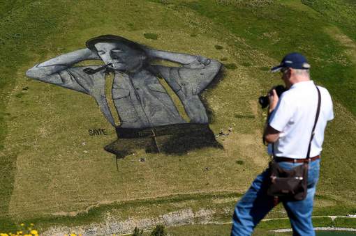 A man photographs a painting, created by French artist Saype and said to be the world's largest biodegradable painting, on the Chaux-de-Mont ski slope above the Alp resort of Leysin on August 4, 2016. The 100 meter long and 100 meter large painting is made with flour, linseed oil, water and biodegradable natural pigments. / AFP PHOTO / Alain Grosclaude / RESTRICTED TO EDITORIAL USE - MANDATORY MENTION OF THE ARTIST UPON PUBLICATION - TO ILLUSTRATE THE EVENT AS SPECIFIED IN THE CAPTION